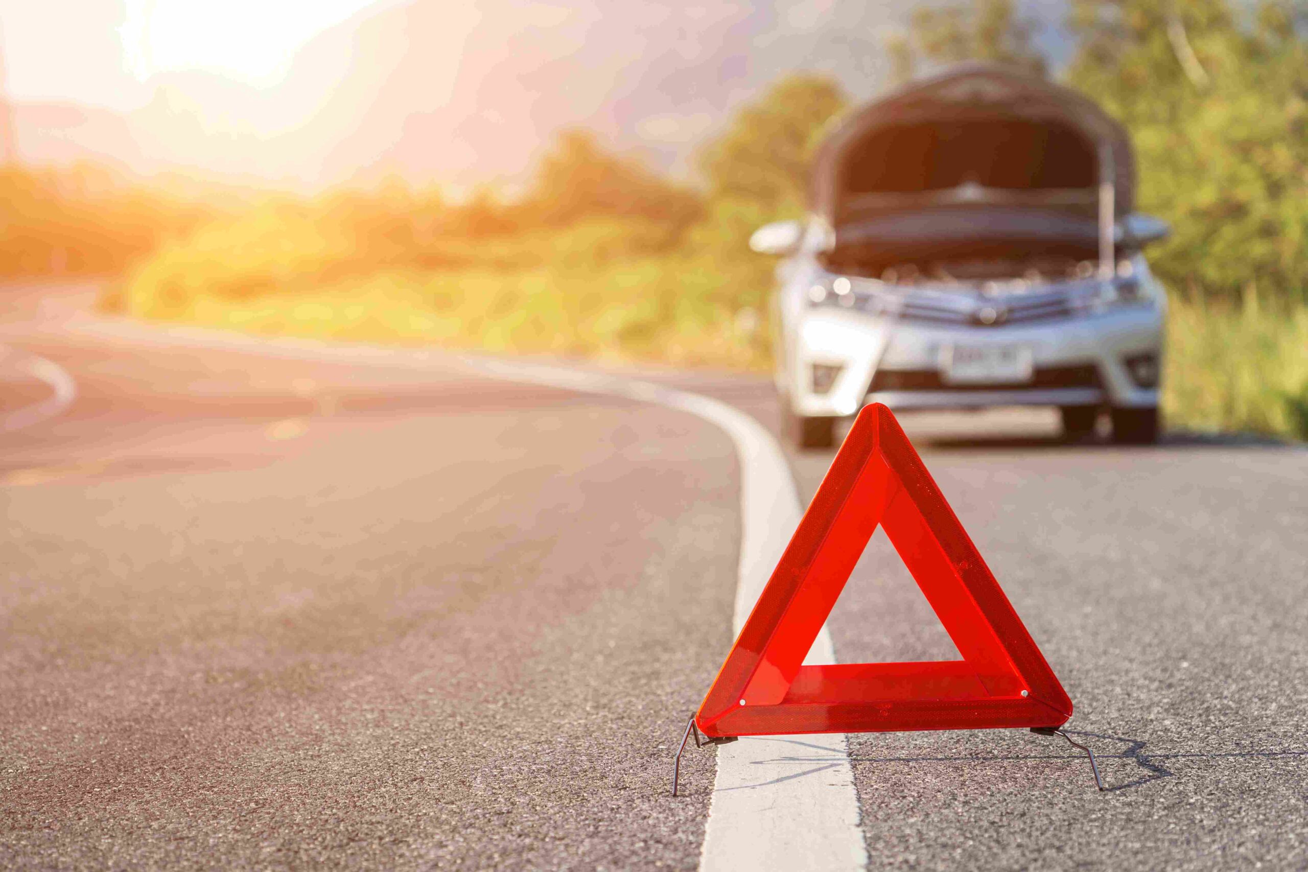 a broken-down car and a hazard triangle in front of it.